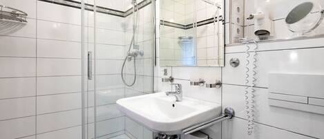 A modern bathroom with a glass shower enclosure, a white sink, and a mirror.