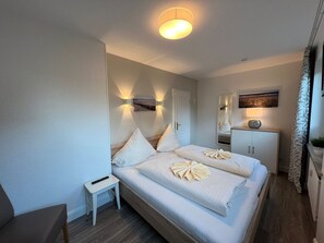 Une chambre d’hôtel moderne avec un grand lit, des tables de chevet, un petit bureau et un miroir.