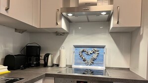 A modern kitchen with a built-in oven, a coffee maker, and a paper towel holder. - By the sea - A modern and bright vacation apartment in the heart of Westerland. (Sylt)