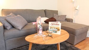 A living room with a grey sofa, a wooden coffee table, and a book titled "Nordsee". - Austernfischerin - A modern and bright vacation apartment in the heart of (Sylt)