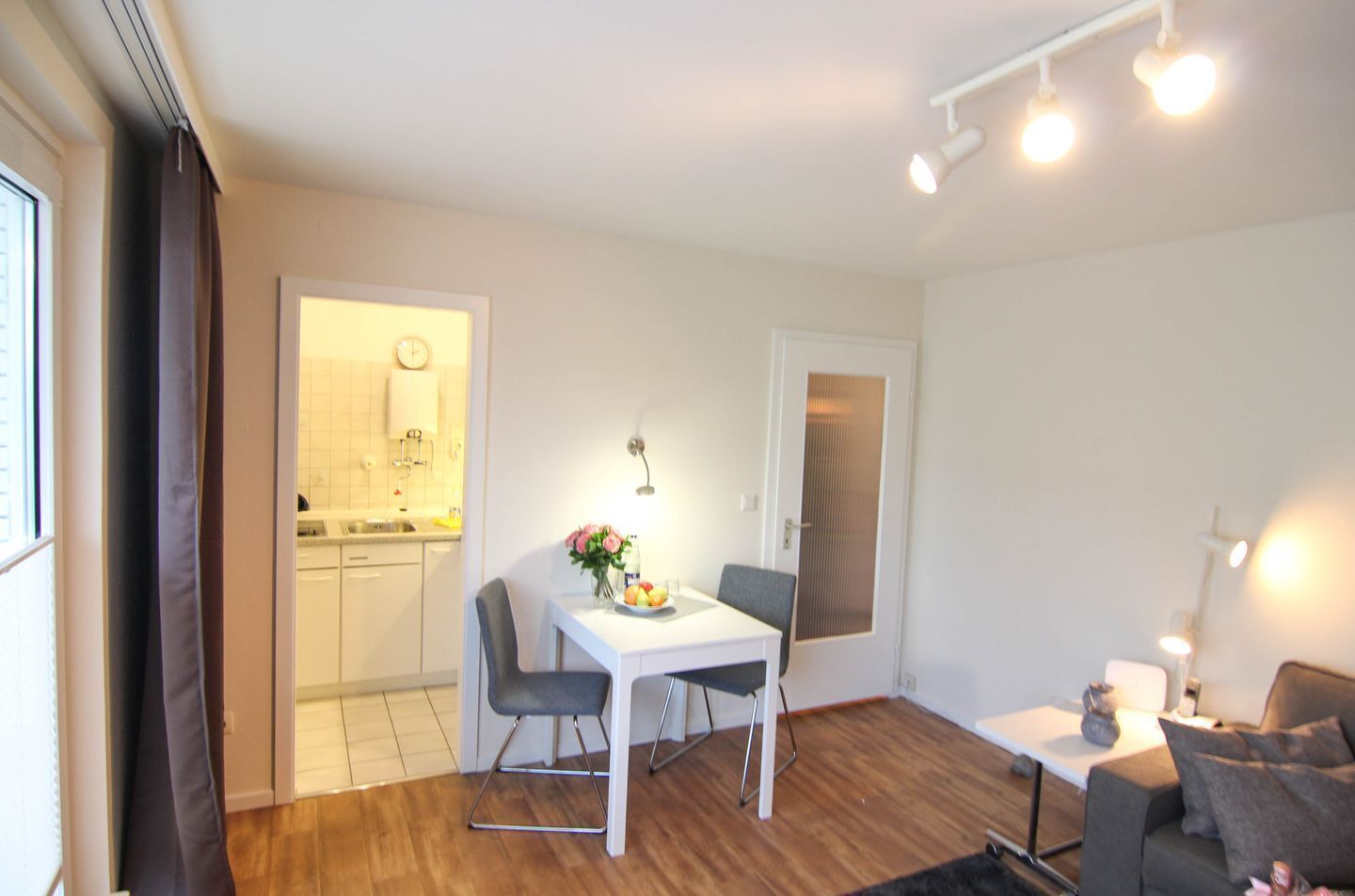 Ein kompakter Wohnraum mit Essbereich, Küchenzeile und einer Sitzecke mit Sofa und kleinem Tisch.