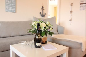 A bottle of wine on a table with a bouquet of flowers, a glass, and a menu or note.