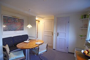 A dining area with a round wooden table, two chairs, a bench, and a hanging light fixture.