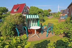 A patio with a striped green and white shelter, a round table, and two chairs.