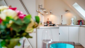 Une cuisine moderne avec des meubles blancs, une cuisinière à gaz et une machine à café.