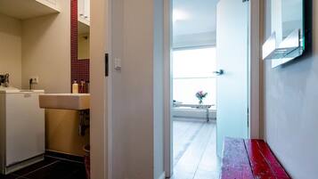 A hallway with a white door leading to a balcony with a view.
