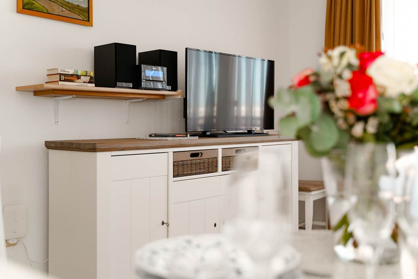 Moderni olohuone, jossa on litteänäyttöinen televisio, valkoinen kaappi ja kirjahylly.