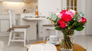 Una cocina moderna con armarios blancos, una mesa de comedor con sillas y un florero sobre una mesa.