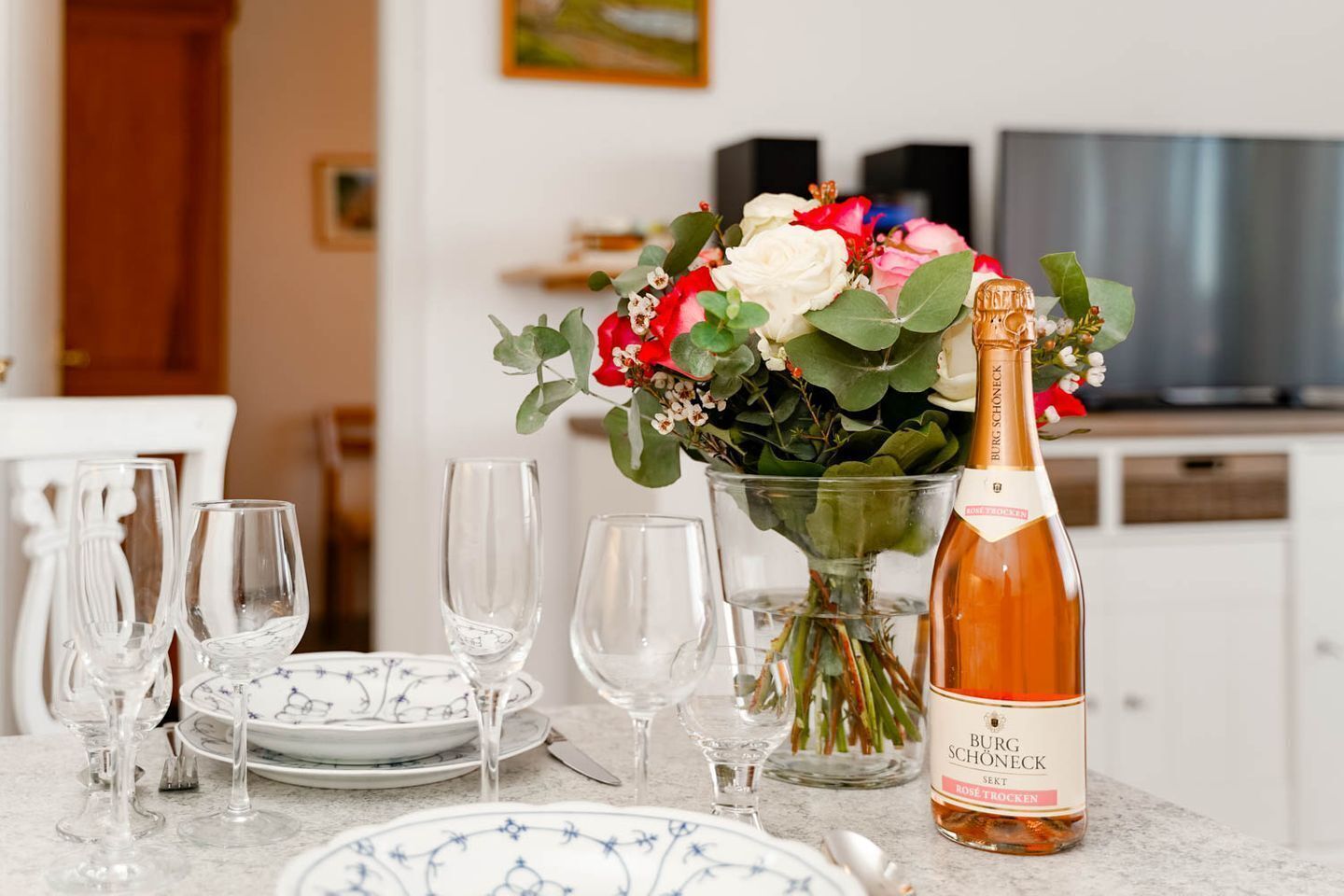 Ein Esstisch mit Weingläsern, Tellern und einer Flasche Rosé Trolken Wein.