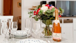 Una mesa de comedor con copas de vino, platos y una botella de vino rosado Trolken.