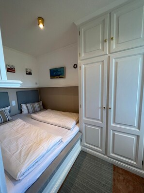 A bedroom with two beds, a wardrobe, a ceiling light, and wall decorations.