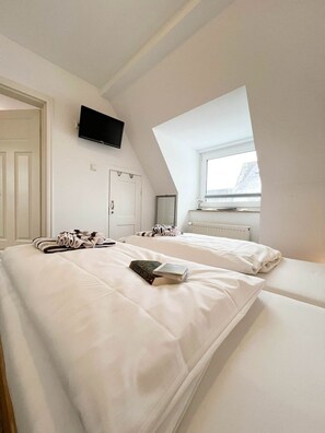 Une chambre à coucher avec un lit, un téléviseur à écran plat, une fenêtre et une porte.