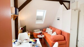 A cozy room with a dining table, white chairs, a sofa, and a small window. - East - Relaxed island life: Cozy vacation apartment in Westerland on Sylt (Sylt)
