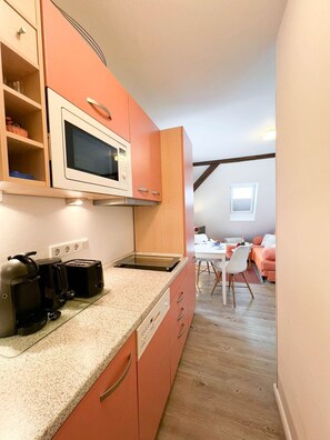 Une cuisine compacte équipée d’un four à micro-ondes, d’un grille-pain et d’une machine à café. Un coin repas avec une table et des chaises est également à disposition.