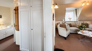Una sala de estar acogedora con un armario blanco, un sofá, una mesa de centro y un ventanal con cortinas.