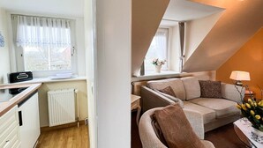 Un espacio habitable pequeño con kitchenette, un sofá y un comedor.