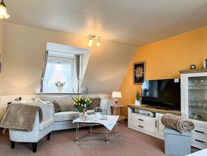 A cozy living room with a sofa, a coffee table, a TV, and a cabinet with glass doors. - Solbeck in the Käpitänshaus Andresen - Sylt is a valuable habitat and (Sylt)
