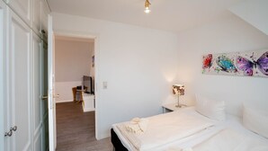 Une chambre à coucher avec un lit, une table de chevet, une lampe et un tableau représentant des papillons.