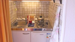 Una cocina compacta con armarios de madera, lavavajillas, pileta y salpicadero de azulejos.