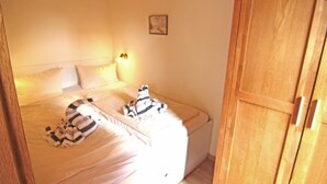 Un dormitorio con cama, almohadas, una mesita de noche y un armario de madera.