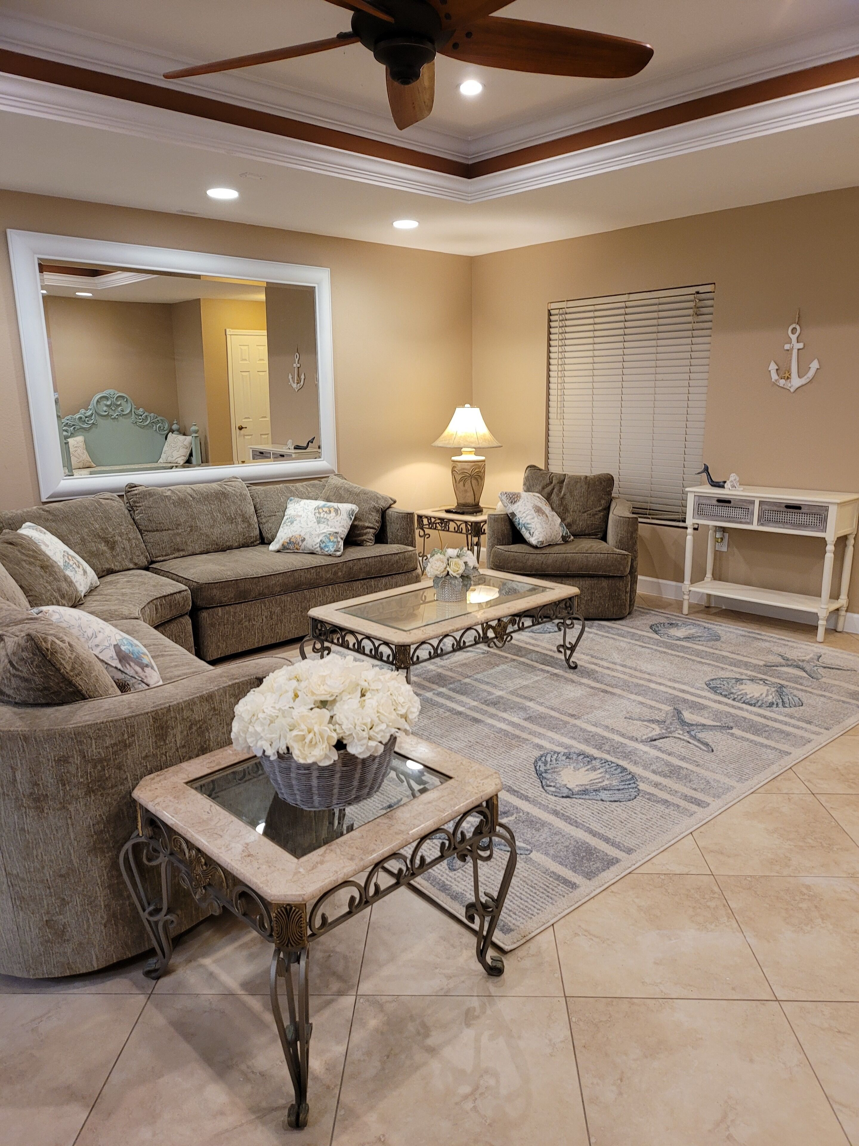 A living room with a sectional sofa, two coffee tables, a floor lamp, and a large mirror.