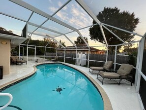 A covered swimming pool with lounge chairs and a patio area.