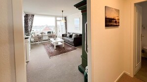 En stue med sofa, sofabord og udsigt over bybilledet gennem store vinduer.