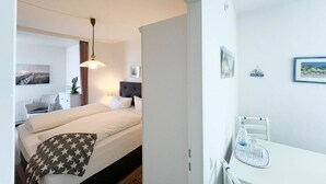Et hotelværelse med seng, natbord, lampe og et skrivebord med stol.