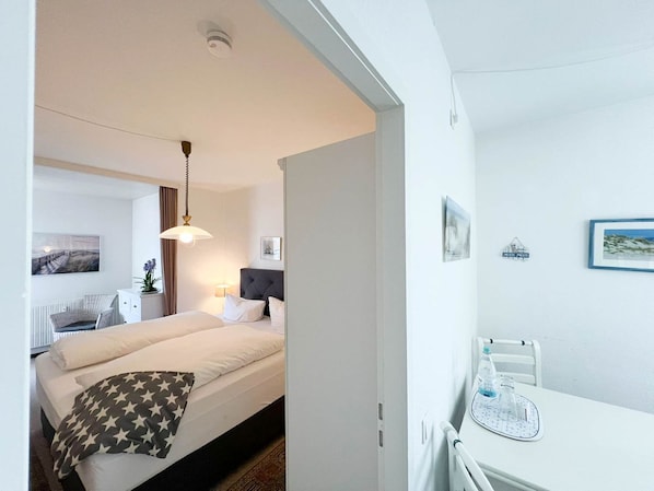 Une chambre d’hôtel comprenant un lit, une table de chevet, une lampe et un bureau avec une chaise.