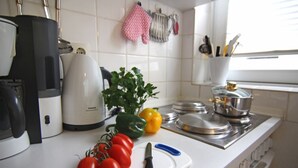 Una cucina con piastrelle bianche, una macchina da caffè Siemens, un tagliere con pomodori e un coltello, e un piano cottura.