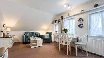 A cozy loft-style living space with a dining area, a sofa, a small table, and a radiator.