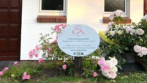 Un bâtiment portant une enseigne indiquant « Hs Thöws » et une autre enseigne commerciale pour « C-A Ferienwohnung GmbH », avec les coordonnées de l’entreprise.