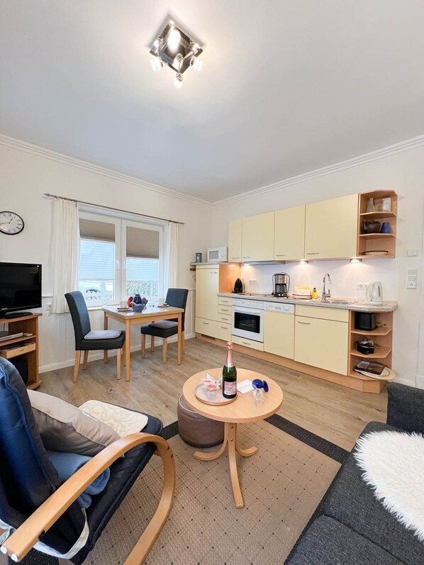 A compact living space with a kitchenette, a dining area, and a seating area with a TV and a sofa.