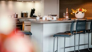 Une cuisine moderne dotée d’un îlot central, de tabourets de bar et de luminaires suspendus.