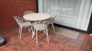 A round table with four chairs, a red brick wall, and a glass door with a curtain.