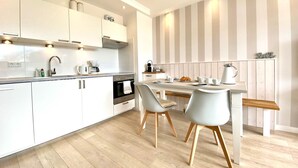 A modern kitchen with white cabinets, a wooden countertop, and a striped wall.