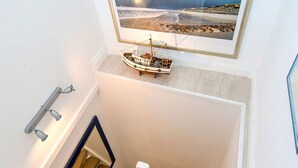Un escalier avec un petit modèle de bateau posé sur une étagère au-dessus.
