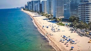 A coastal hotel with a beachfront view, multiple balconies, and a pool area. - Beachfront condo-We are on the Beach-Views every window-Patio Pool-No resort fee (Fort Lauderdale)