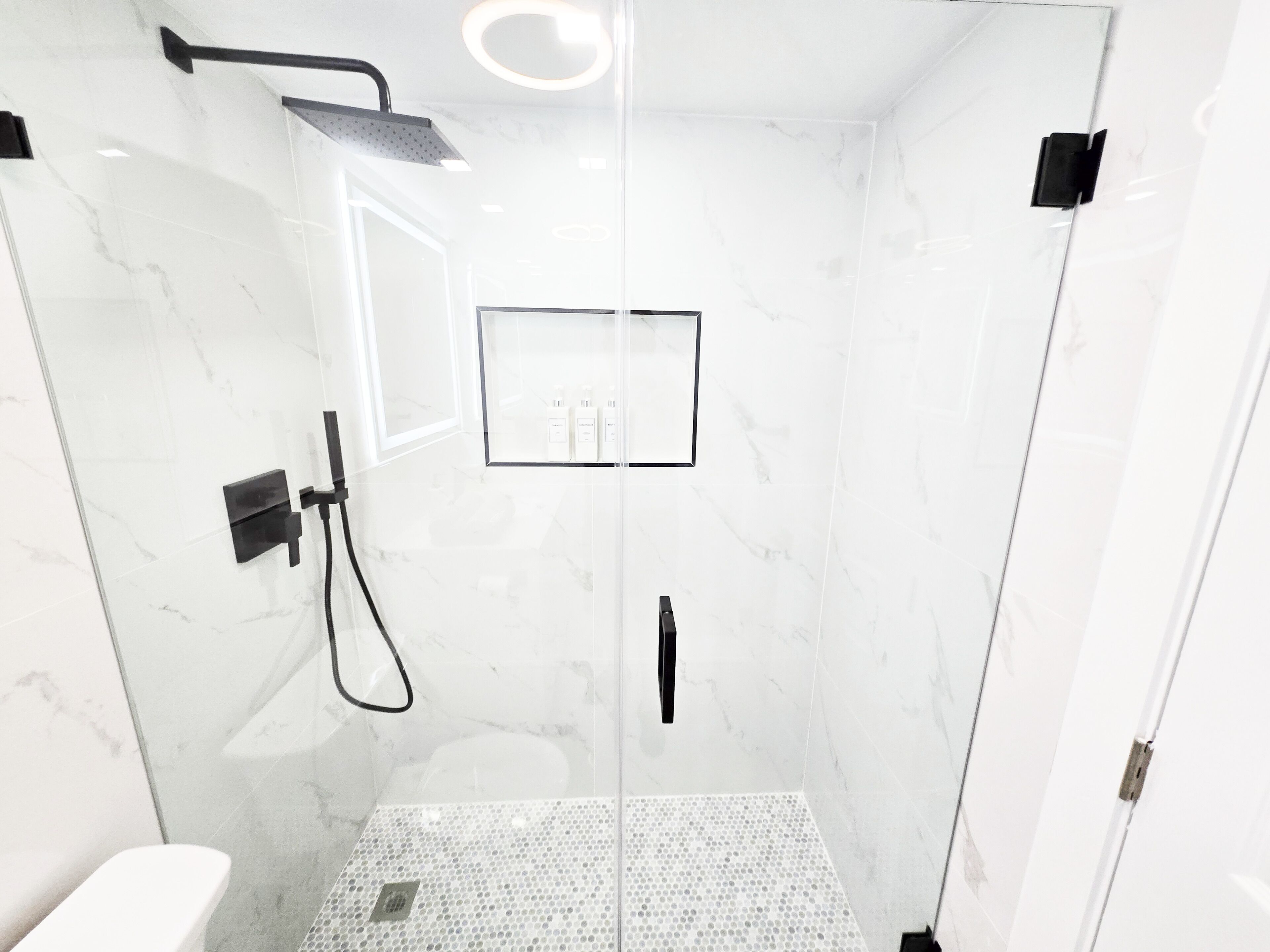 Une salle de bain moderne avec une douche à parois de verre, des toilettes et un lavabo.