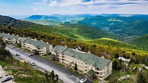 A multi-story hotel with a parking lot and a view of the surrounding mountains.