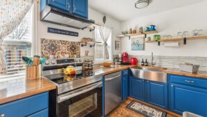 Een moderne keuken met blauwe kastjes, roestvrijstalen apparatuur en decoratieve tegels.