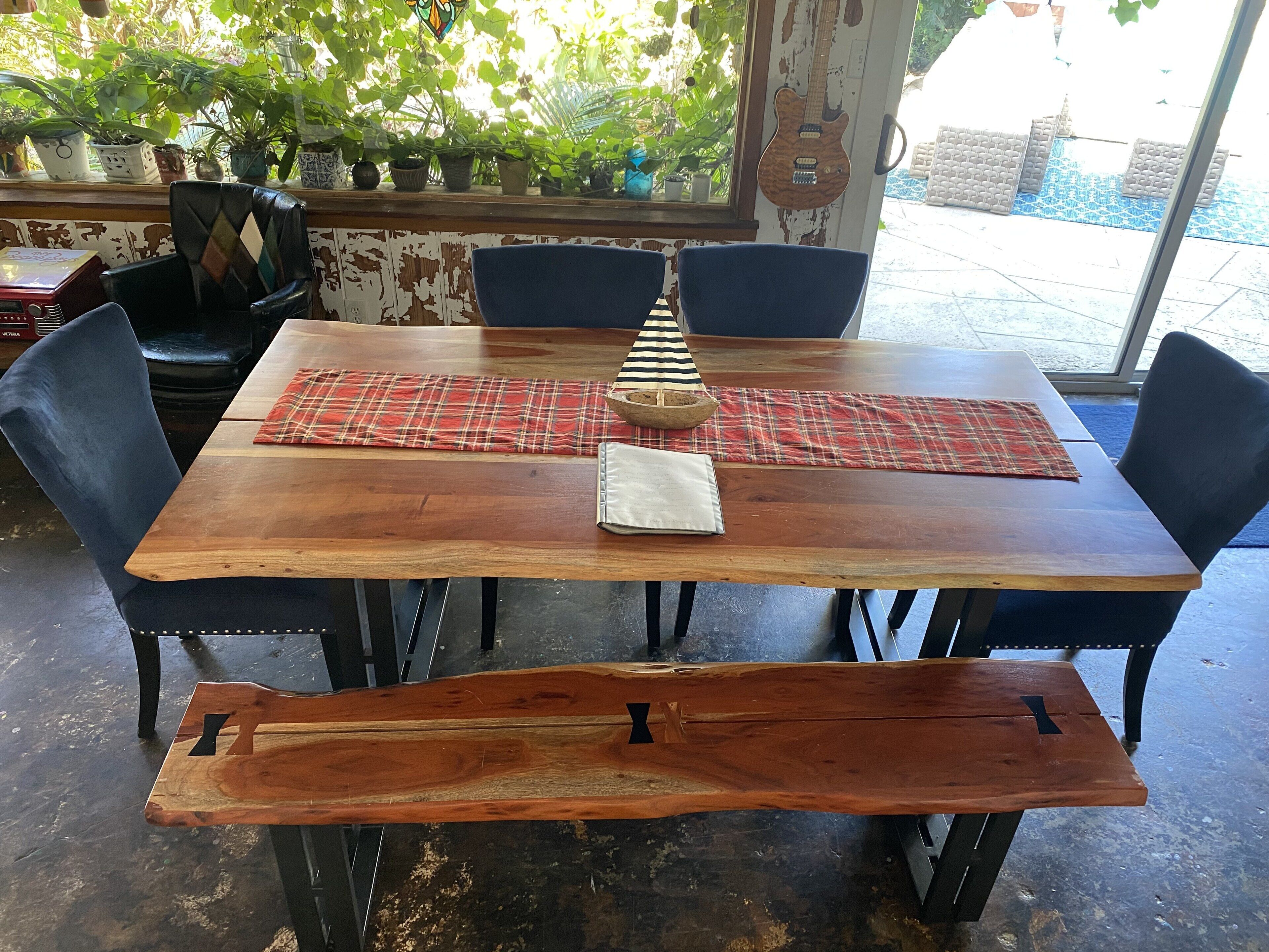 Un tavolo da pranzo in legno con un sottopiatti a quadri, sedie nere e una panca.