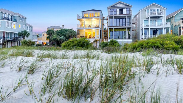 Une propriété située en bord de mer, comprenant des maisons à plusieurs étages dotées de balcons, une plage de sable et une végétation côtière.