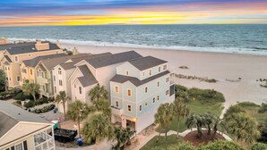 Un quartier résidentiel situé en bord de mer, avec de nombreuses maisons, une plage de sable et un coucher de soleil sur l’océan.