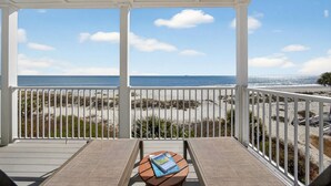 Un balcon fermé offrant une vue sur la plage et l’océan.
