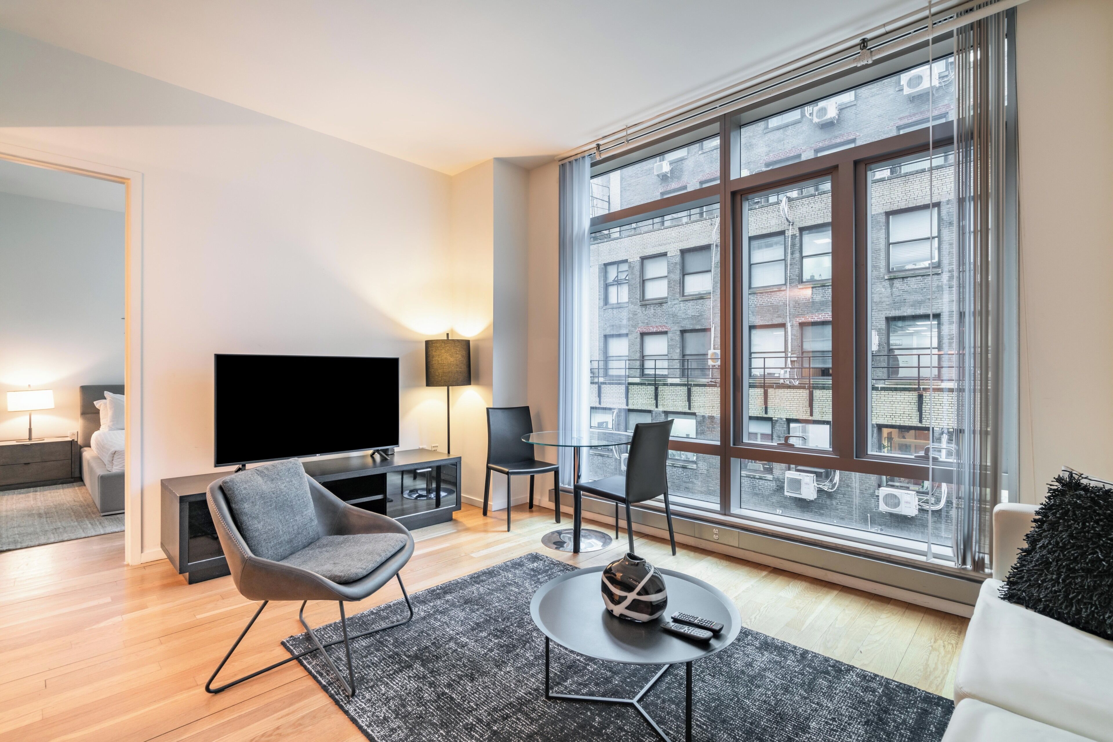 A modern living room with a large window, a flat-screen TV, and a seating area with a coffee table.