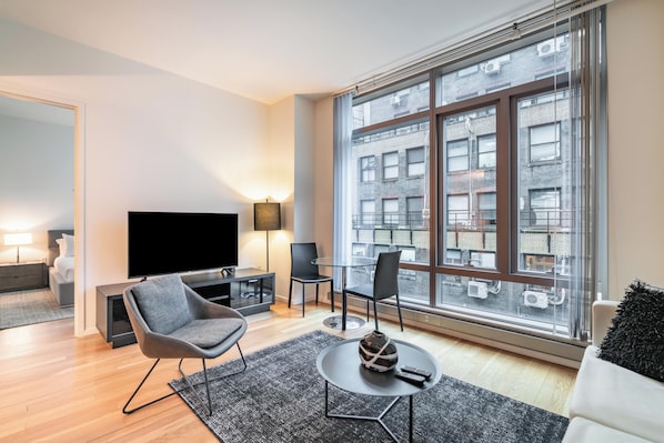 A modern living room with a large window, a flat-screen TV, and a seating area with a coffee table.