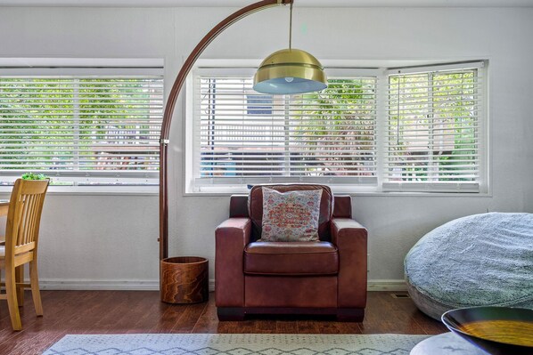 A room with a brown leather chair, a wooden chair, a round ottoman, and a floor lamp. - Waterfront Front Row Seats to Nature’s Best Show (Spring Hill)