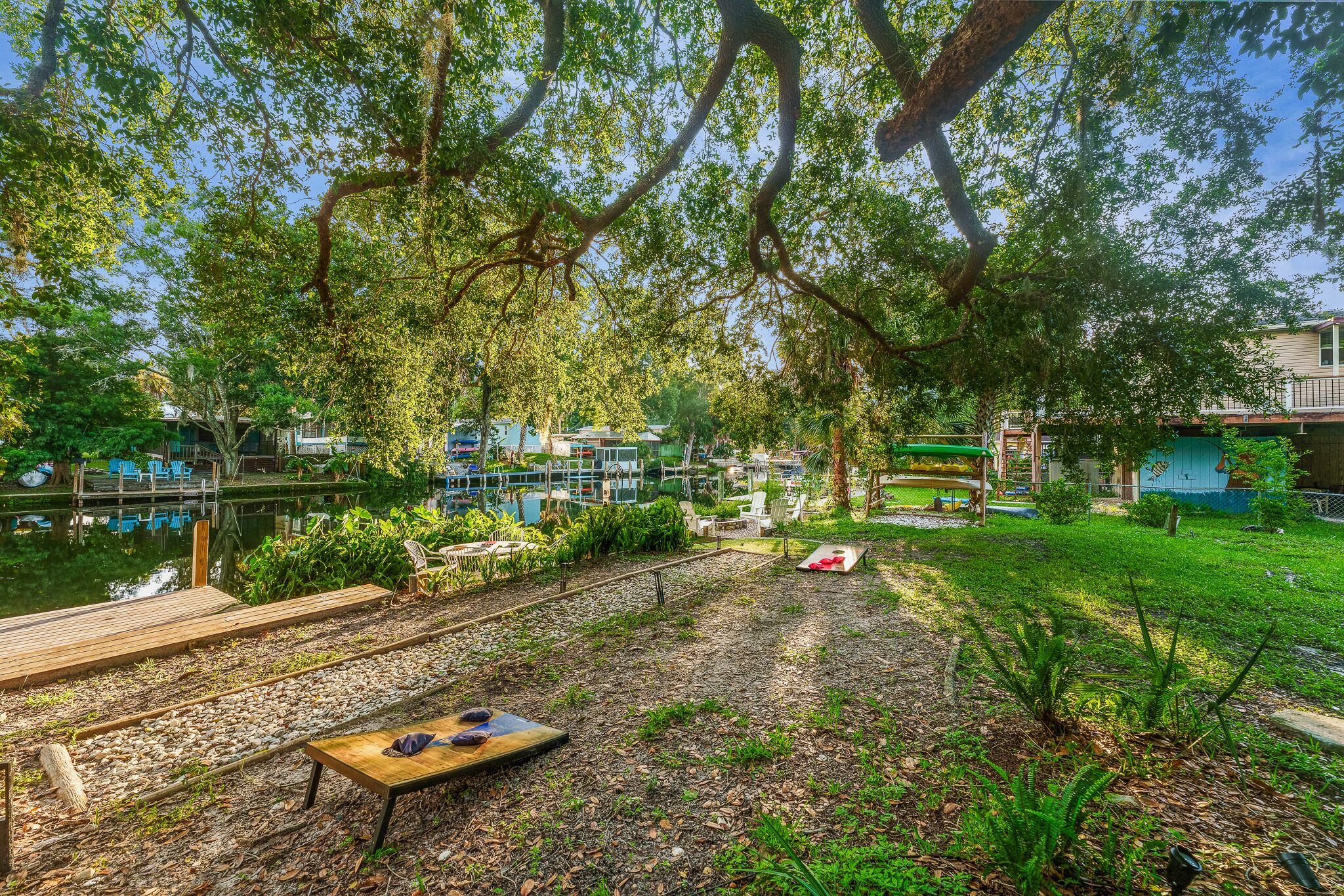 Zona exterior tranquil·la amb terrassa de fusta, taula i cadires, i un petit jardí amb plantes diverses.