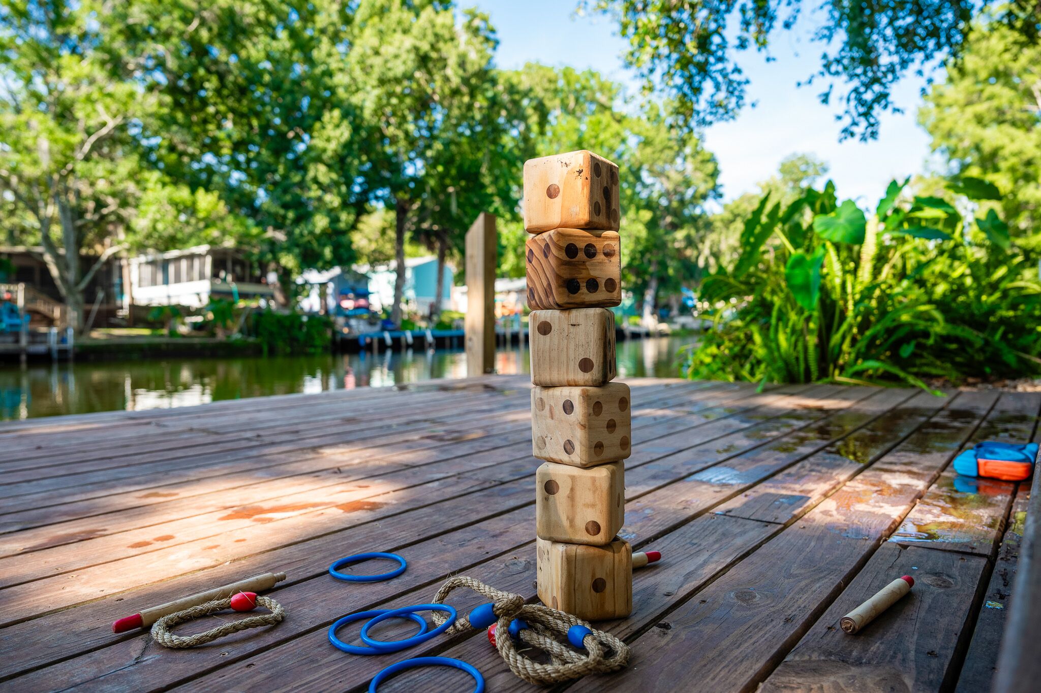 A wooden deck with a wooden tower of dice, ropes, and a blue and orange object.